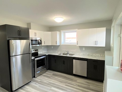 an empty kitchen with stainless steel appliances and white cabinets